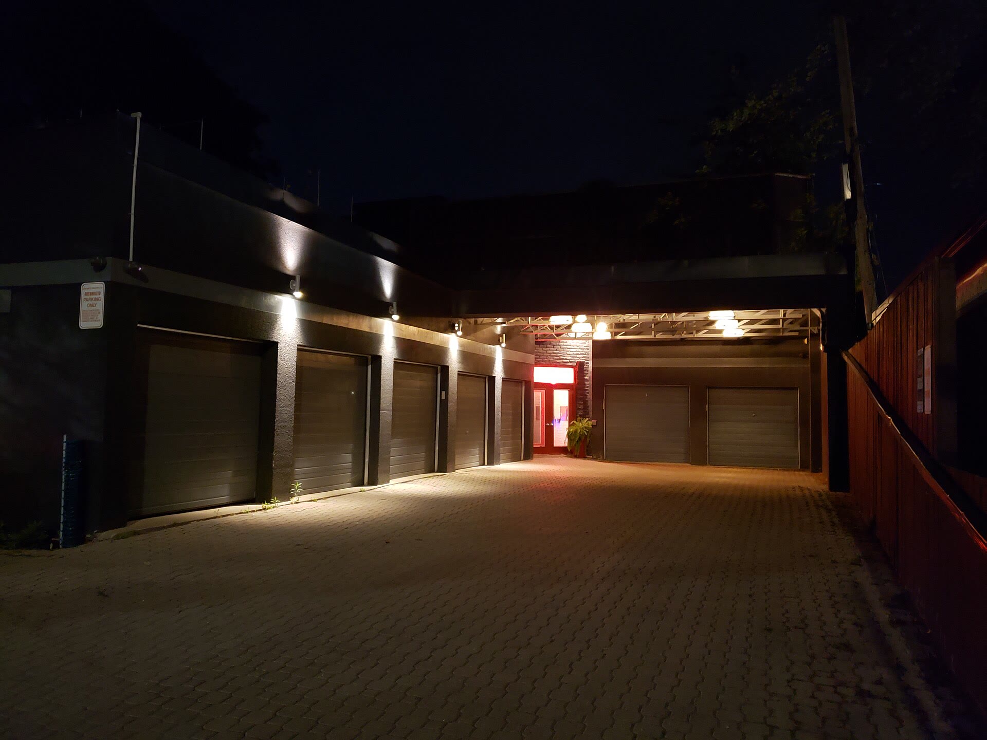 Fileira de portões de garagem iluminados por luzes na parede, à noite