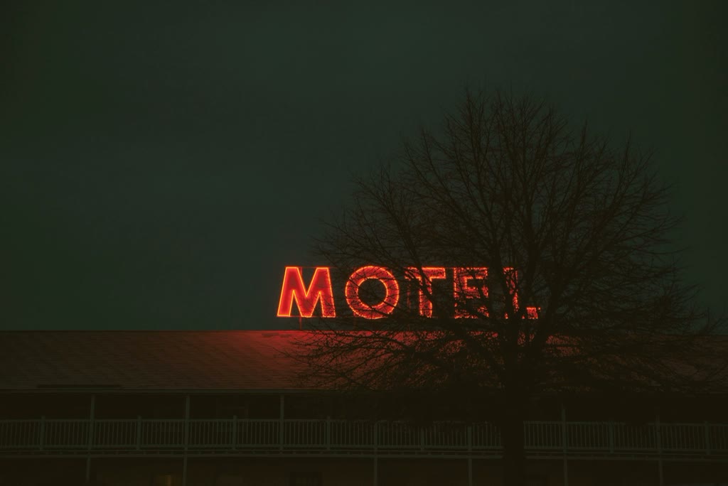 Letreiro luminoso vermelho escrito MOTEL numa noite de neblina